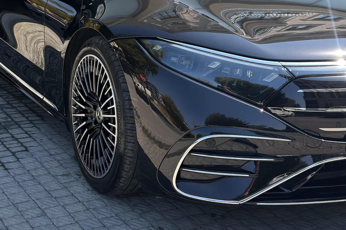 Siyah Mercedes-Benz’in ön çamurluğu ve jantı, boyada çevrenin yansıması
