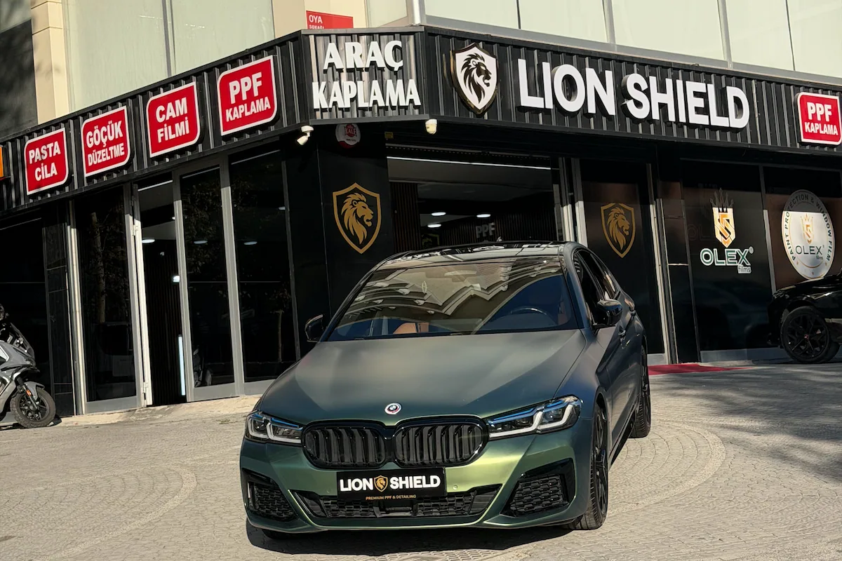Lion Shield uygulama merkezinin girişi ve önünde duran mat yeşil BMW 5 Serisi